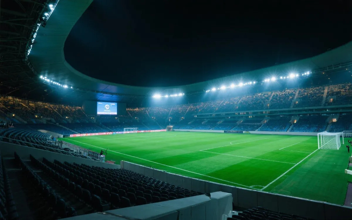 现代大型足球场夜景，观众席灯光与草坪形成强烈对比的电影感画面